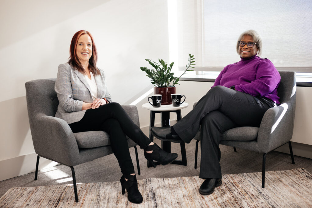 Some of GCI's women in leadership, Anna Gould and Deborah Ferrell, sitting in chairs.