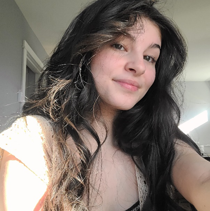 woman with curled dark hair smiling at the camera.